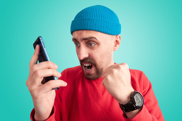 Expressive guy worrying while watching on screen of smartphone
