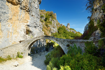 Fototapeta na wymiar Traditional arched stone bridge of Zagori region in Northern Greece. Iconic bridges were mostly built during the 18th and 19th centuries by local master craftsmen using local stone.