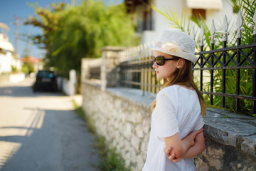 Cute young girl having fun outdoors on warm and sunny summer day during family vacations in Greece