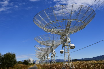 Array of satellite dishes or radio antennas against sky. Space observatory.
