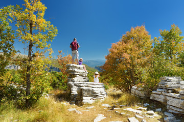 Father and kids exploring Stone forest, natural rock formation, created by multiple layers of stone, located near Monodendri village in Zagori region, Northern Greece.