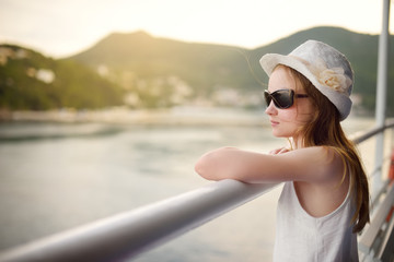 Adorable young girl enjoying ferry ride staring at the sea on sunset. Child having fun on summer family vacation in Greece.