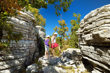 Two young girls exploring Stone forest, natural rock formation, created by multiple layers of stone, located near Monodendri village in Zagori region, Northern Greece.