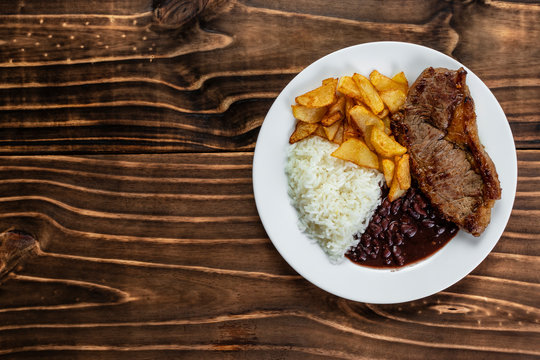 meal on white plate, rice, beans, steak and chips, Wooden Background