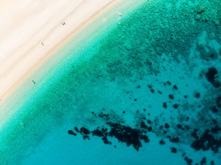 Aerial top down view of Myrtos beach, the most famous and beautiful beach of Kefalonia, a large coast with turqoise water and white coarse sand, surrounded by steep cliffs.