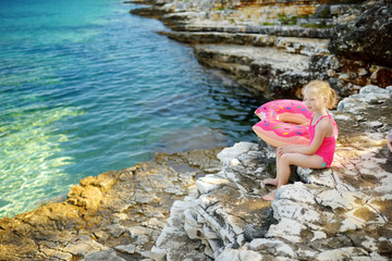 Cute little girl having fun at Emplisi Beach, picturesque stony beach in a secluded bay, with clear waters popular for snorkelling.