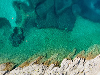Aerial top down view of Emplisi Beach, picturesque stony beach in a secluded bay, with clear waters popular for snorkelling. Small pebble beach near Fiscardo town of Kefalonia, Greece.