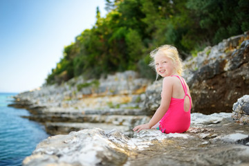 Cute little girl having fun at Emplisi Beach, picturesque stony beach in a secluded bay, with clear waters popular for snorkelling.