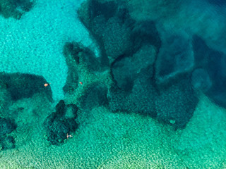Aerial top down view of Emplisi Beach, picturesque stony beach in a secluded bay, with clear waters popular for snorkelling. Small pebble beach near Fiscardo town of Kefalonia, Greece.