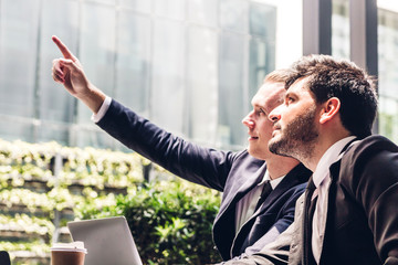 Image of two businessman coworkers in black suit talking and working with laptop computer and discussing something together at the cafe.Businessman teamwork and Partnership concept