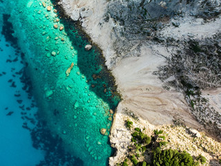 Scenic aerial top down view of picturesque jagged coastline of Kefalonia with clear turquoise waters, surrounded by steep cliffs.