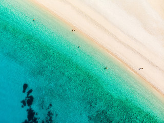 Aerial top down view of Myrtos beach, the most famous and beautiful beach of Kefalonia, a large coast with turqoise water and white coarse sand, surrounded by steep cliffs.