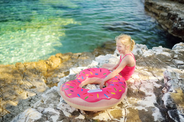 Cute little girl having fun at Emplisi Beach, picturesque stony beach in a secluded bay, with clear waters popular for snorkelling.