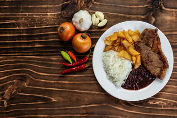 meal on white plate, rice, beans, steak and chips, Wooden Background