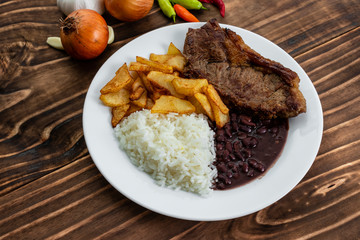 meal on white plate, rice, beans, steak and chips, Wooden Background