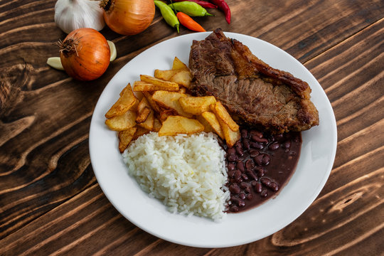 meal on white plate, rice, beans, steak and chips, Wooden Background