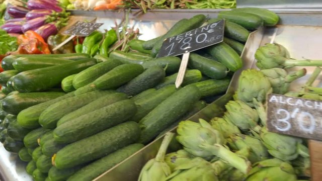 In Spain, the market on the counter fresh juicy beautiful vegetables - peppers, cucumbers, artichokes, potatoes, different types of tomatoes. Shot in motion