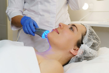 Obraz na płótnie Canvas Hardware cosmetology. Ultrasound chromotherapy. Beautician carries out procedure for tightening skin of face. Spa.