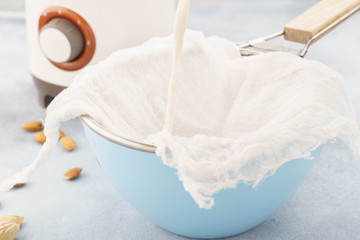 Homemade nut milk making process. Pouring milk into cloth.