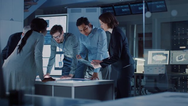 Engineers Meeting in Technology Research Laboratory: Engineers, Scientists and Developers Gathered Around Illuminated Conference Table, Talking and Finding Solution. Industrial Design Facility 