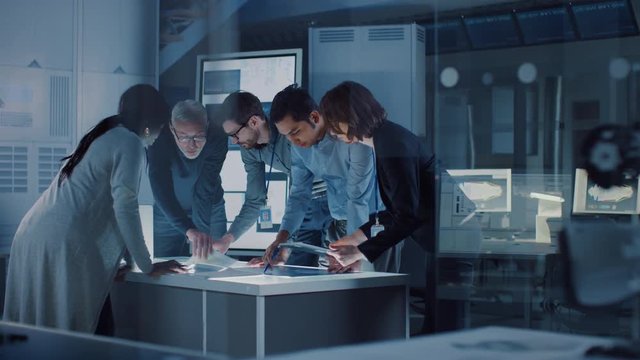 Engineers Meeting in Technology Research Laboratory: Engineers, Scientists and Developers Gathered Around Illuminated Conference Table, Talking and Finding Solution. Industrial Design Facility 