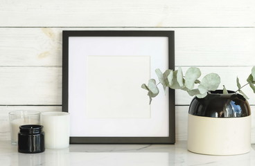 frame mock up and dry eucalyptus twigs in vase on desk.