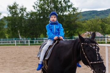 six-year-old boy sits on a black horse