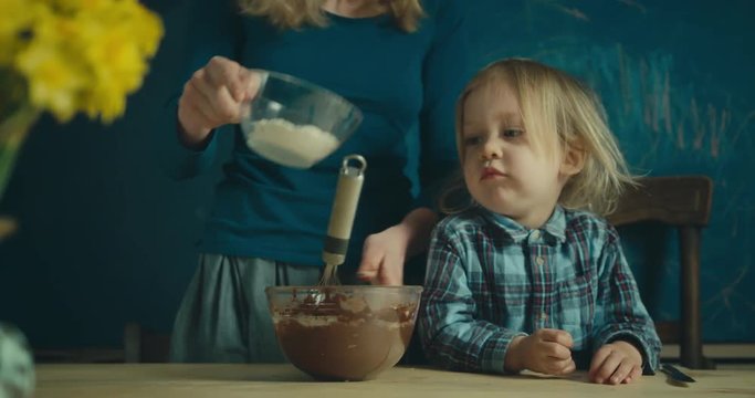 Mother and toddler mixing dough for a cake