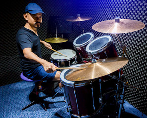 Fototapeta na wymiar man put black t-shirt to playing the drum set with wooden drumsticks in music room