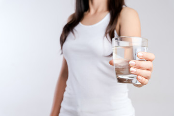 A glass of clean mineral water in woman's hands. Concept of environment protection, healthy drink and healthcare.