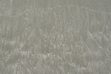 Background and texture photo of gray color wet sand with shape from the sea on the beach.
