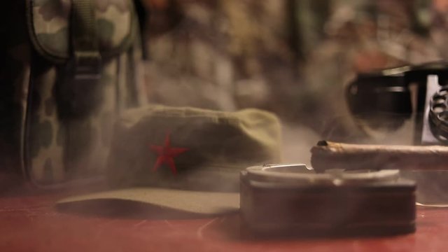 Close up of a Cuban cigar and ashtray on the wooden table. Communist dictator commander table in dark room. Army general`s work table concept. Artwork decoration