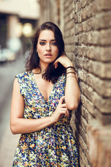 Fototapeta premium Girl with blue eyes standing next to brick wall outdoors