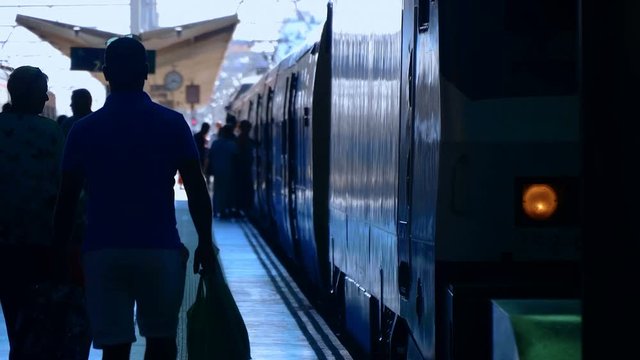 At the rail station, at the platform there are two trains and passengers are calmly walking and standing on the platform - it is not yet time for the train to departure