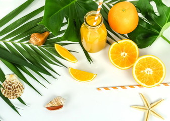 summer drinks background top view, orange juice, sunglasses, palm leaves, seashells on white background. Copy space.