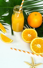 summer drinks background top view, orange juice, sunglasses, palm leaves, seashells on white background. Copy space.