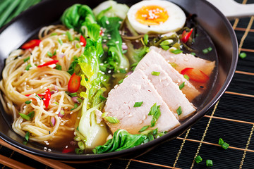 Miso Ramen Asian noodles with egg, pork and pak choi cabbage in bowl on dark background. Japanese cuisine.