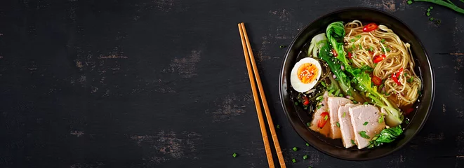 Miso Ramen asiatische Nudeln mit Ei, Schweinefleisch und Pak-Choi-Kohl in Schüssel auf dunklem Hintergrund. Japanische Küche. Ansicht von oben. Banner © timolina