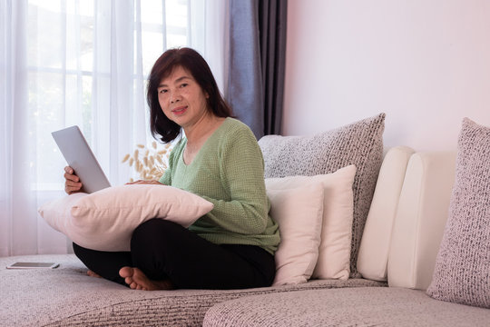 Beautiful Girl At Home Using Laptop On The Couch, Elderly Asian Woman.