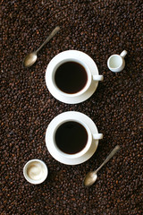 Two coffee cups on coffee bean background still life image.