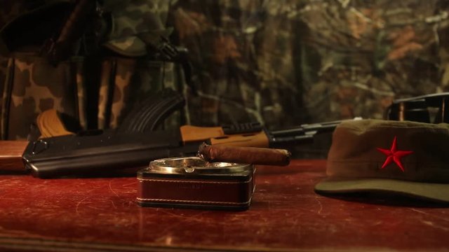 Close up of a Cuban cigar and ashtray on the wooden table. Communist dictator commander table in dark room. Army general`s work table concept. Artwork decoration
