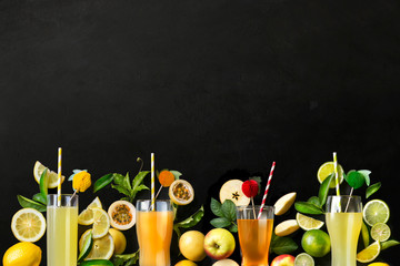 Various fresh fruits and juice in glass border on black background.