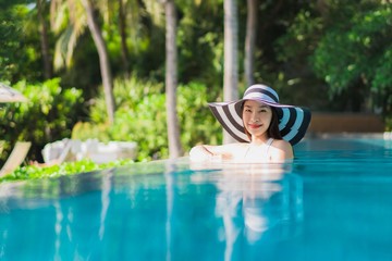 Portrait beautiful young asian woman happy smile in swimming pool around resort and hotel