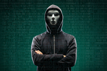 Computer hacker in mask and hoodie over abstract binary background. Obscured dark face. Data thief, internet fraud, darknet and cyber security.