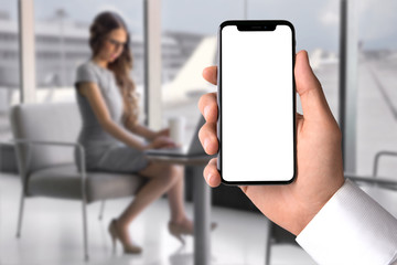 Business man hand holding latest smart phone, blank screen, VIP priority lounge at airport