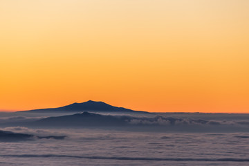 Fototapeta premium Beautifully colored sky at dusk, with mountains layers and mist between them