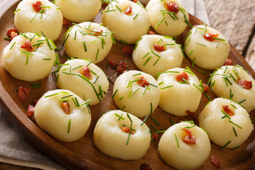Homemade round potato dumplings with bacon and green onions close-up on a plate. horizontal