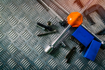 Top view of tools on industrial metal checker plate. Metal checkerplate for anti skid. Nut, bolts, and hex key on metal sheet floor. Silver bump ground with art pattern. Silver texture background.