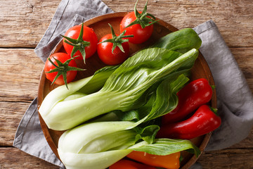 raw healthy baby bok choy, tomatoes and peppers closeup on a plate. Horizontal top view