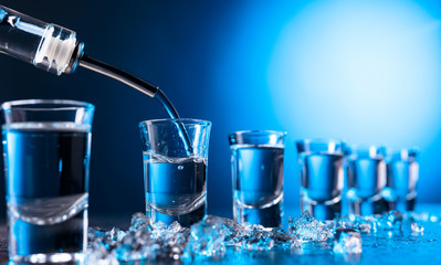 Vodka poured into a glass lit with blue backlight.